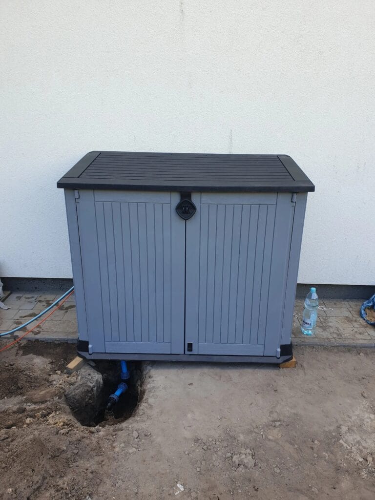 Pompa ssąca (zestaw hydroforowy) ukryta w estetycznej obudowie ogrodowej (Keter / Lifetime), z przyłączem rur PE z wykopu.