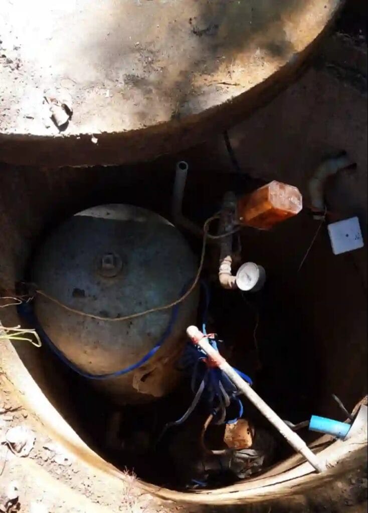 Błędny montaż zbiornika ocynkowanego i automatyki pompowej wewnątrz wilgotnej, nieszczelnej komory studziennej, co grozi korozją i zamarznięciem.