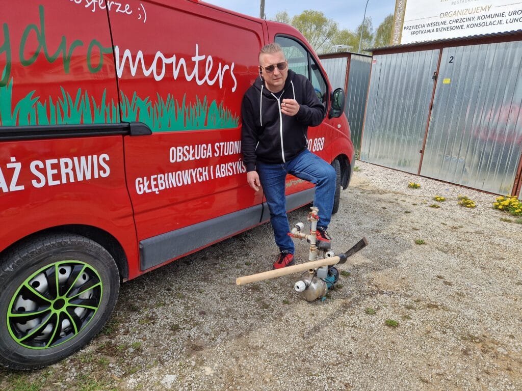 Instalator i założyciel Hydromonters.pl przy czerwonym wozie serwisowym (VAN), gotowy do serwisu pompy abisyńskiej.