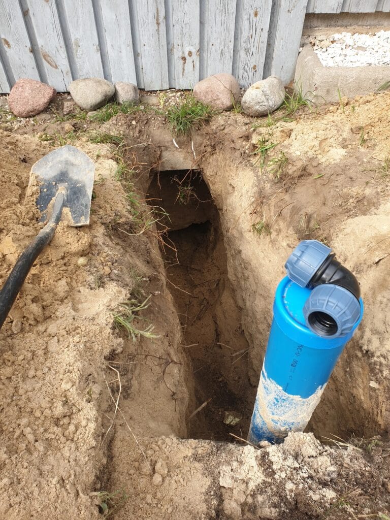 Niebieska rura osłonowa studni głębinowej z zamontowanym kolankiem PE, gotowa do rozpoczęcia głębokiego wykopu pod przyłącze wodne (poniżej strefy przemarzania).