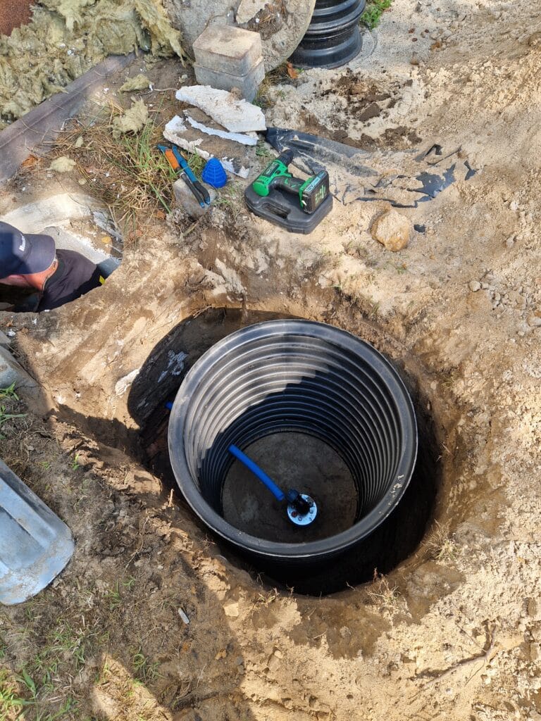 Montaż obudowy studni głębinowej (czarna rura karbowana) w celu stworzenia suchej komory rewizyjnej wokół hermetycznej głowicy (niebieska).