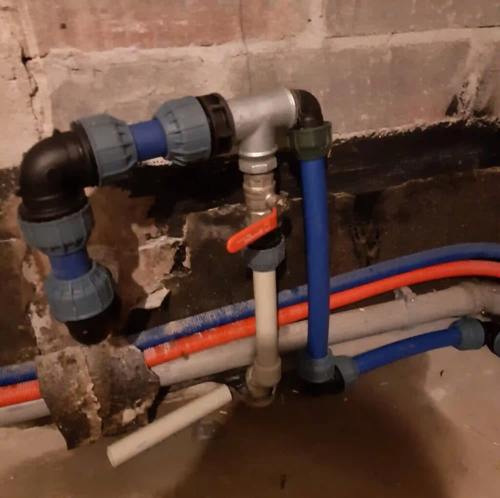 Przejście przyłącza wodnego (niebieska rura PE) przez fundament i podłączenie do instalacji wewnętrznej (rura PP) z głównym zaworem odcinającym.