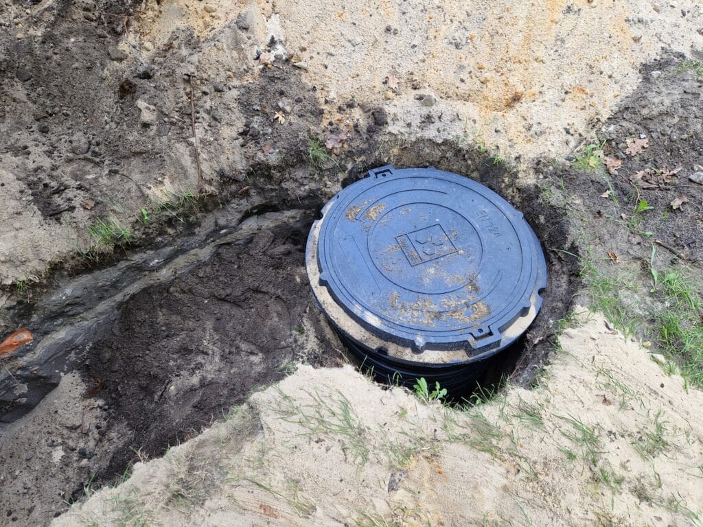 Sterylne zakończenie instalacji: obudowa studni głębinowej (rura karbowana) z włazem rewizyjnym (pokrywą), gotowa do zasypania.