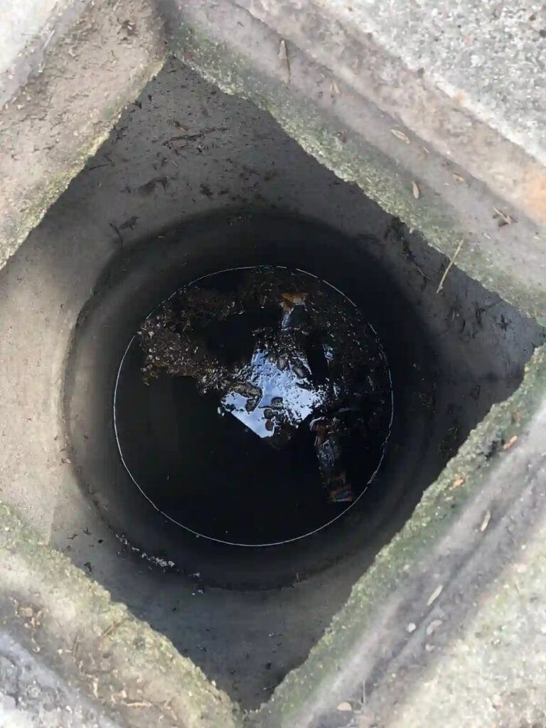 Nieszczelna studnia kręgowa zalana zanieczyszczoną wodą powierzchniową, zagrażająca zanurzonej pompie głębinowej.