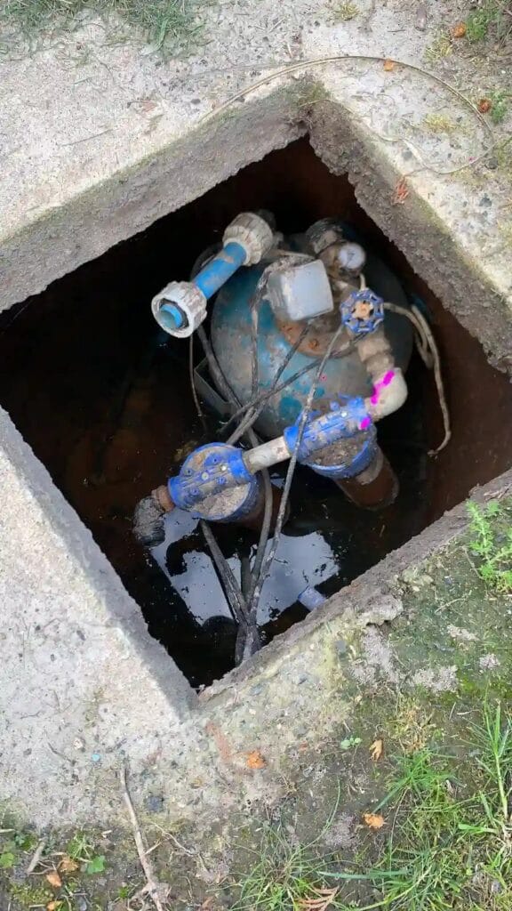 Katastrofalny błąd: cały osprzęt pompy głębinowej (zbiornik przeponowy, wyłącznik ciśnieniowy) utopiony w wodzie i błocie w nieszczelnej studni.