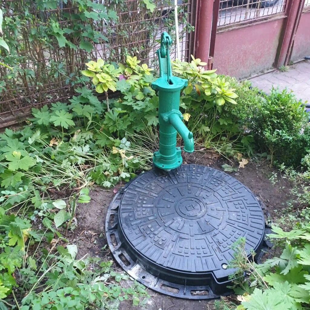 Hybrydowy system wodny: zielona pompa ręczna ("abisynka") jako awaryjny "backup" dla pompy głębinowej (ukrytej pod włazem).