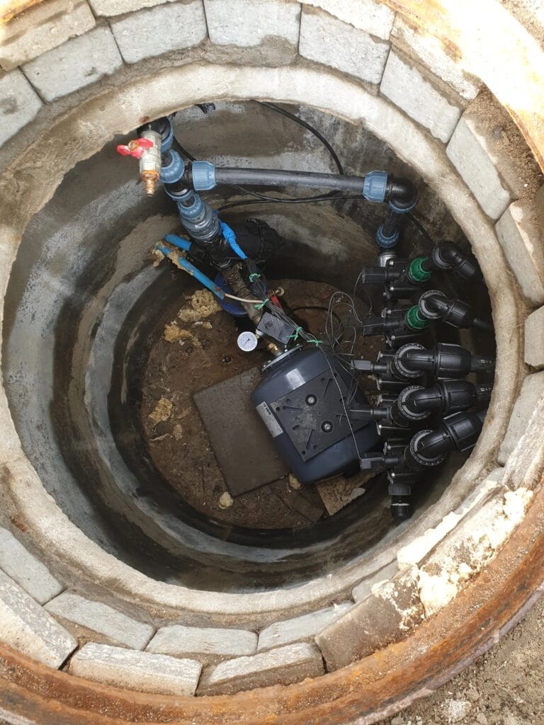 Prawidłowy montaż: Kolektor elektrozaworów i zbiornik buforowy GWS PressureWave (szary) umieszczone poniżej strefy przemarzania w suchej komorze betonowej.