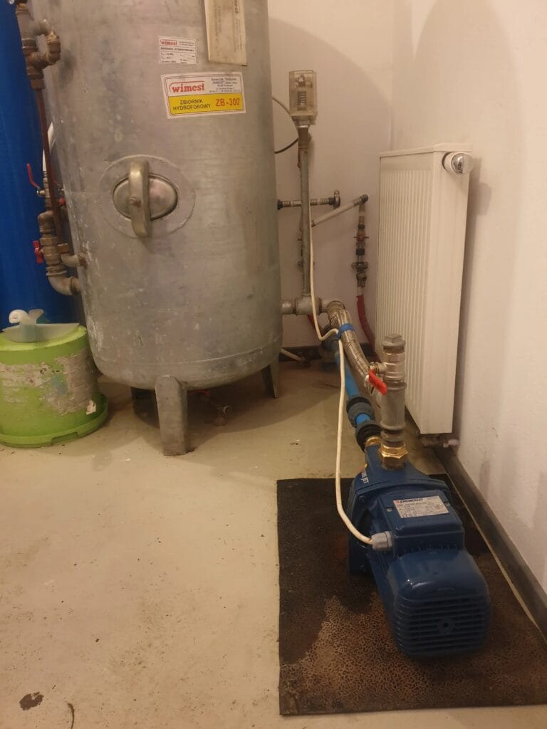 Profesjonalny montaż zestawu hydroforowego premium w kotłowni; widoczna pompa hydroforowa Pedrollo Future Jet połączona elastycznym wężem antywibracyjnym z dużym, pionowym zbiornikiem ocynkowanym Wimest 300 litrów. Czysta i estetyczna instalacja.