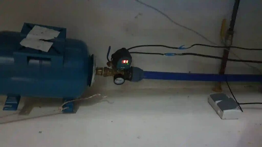 Monumentalny błąd: prowizoryczna instalacja hydroforowa z automatem elektronicznym i zbiornikiem, z luźnymi kablami 230V na podłodze.