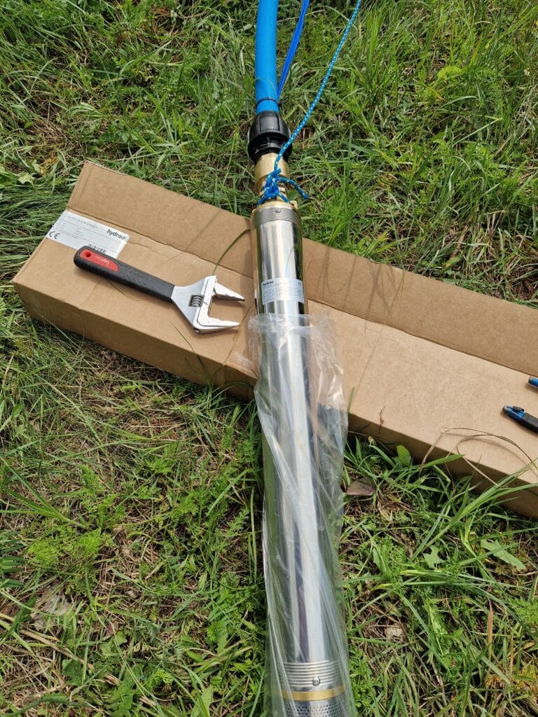 Proces "uzbrajania" nowej pompy głębinowej premium Hydroo (stal nierdzewna), z podłączoną rurą PE i niebieską linką asekuracyjną.