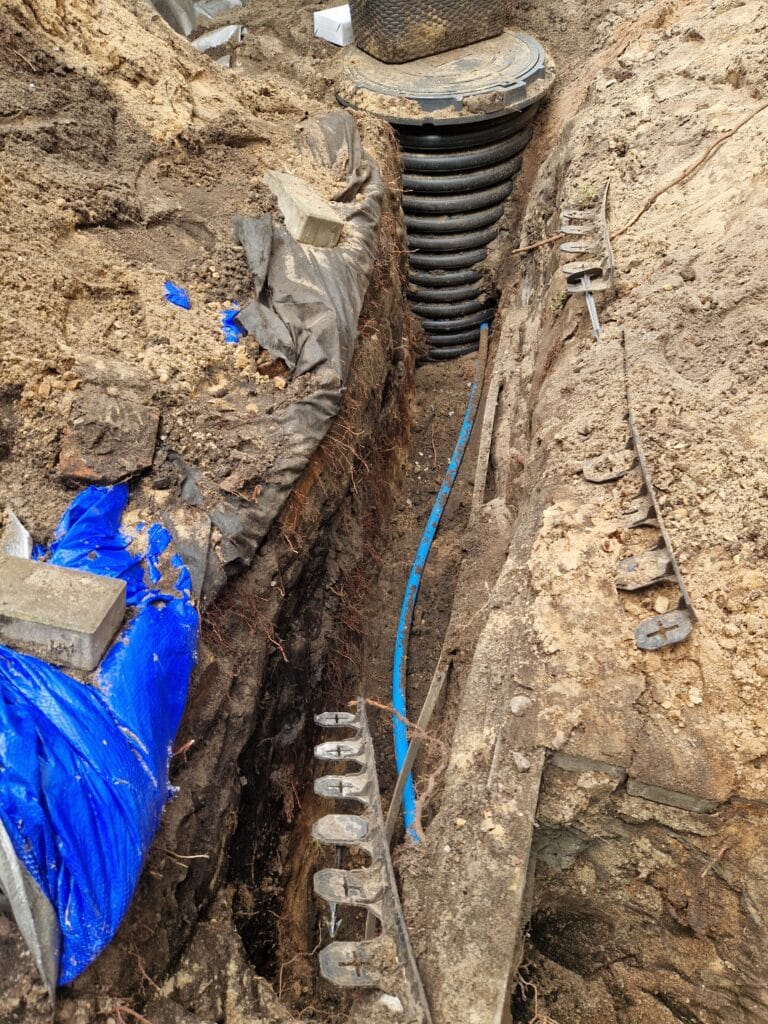 Efekt ciężkiej pracy ręcznej: głęboki, precyzyjny wykop pod przyłącze wodne (rura PE), wykonany ręcznie w trudnych warunkach gruntowych.