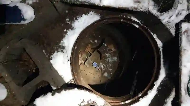 Ekspert Hydromonters.pl wykonuje serwis awaryjny studni głębinowej zimą, w nocy lub w trudnych warunkach pogodowych. Otwarty właz studni rewizyjnej otoczony śniegiem.