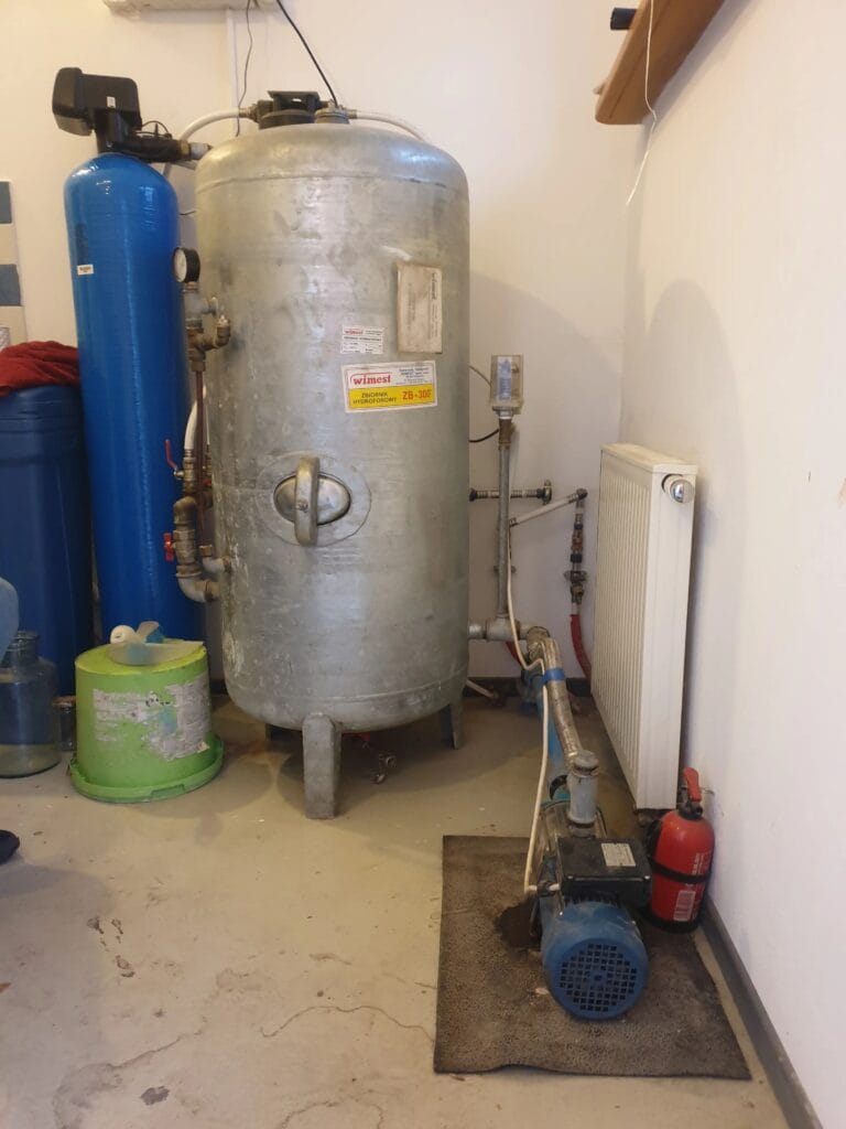 Archaiczny, ogromny zbiornik ocynkowany (Winest) i mała pompa powierzchniowa w kotłowni. System jest nieefektywny i grozi awarią.