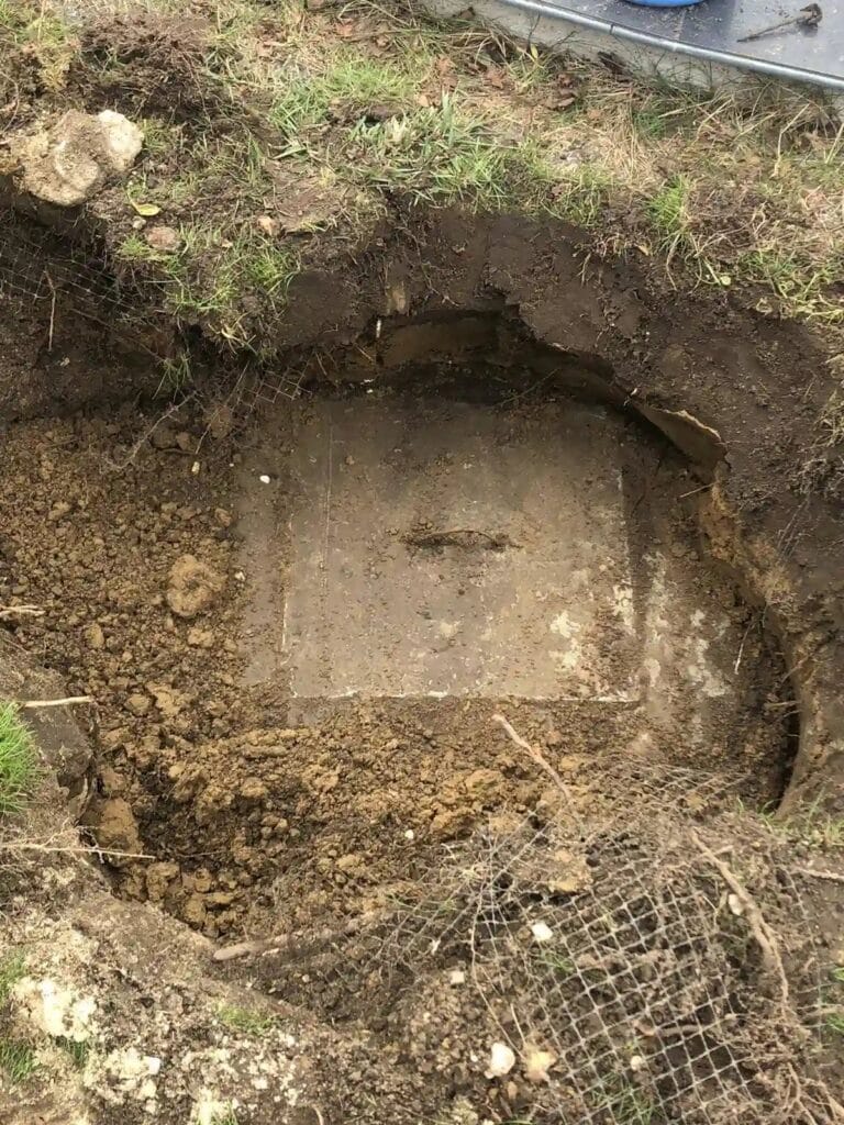 Krytyczny błąd: pokrywa studni głębinowej zakopana pod trawnikiem i siatką na krety, co uniemożliwia serwis pompy i grozi skażeniem.