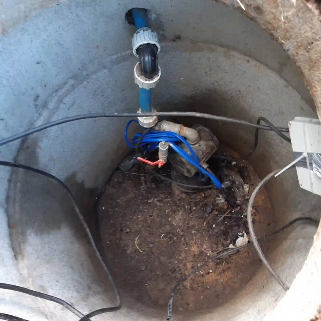 Krytyczny błąd: sterownik premium Grundfos PM1 zainstalowany na dnie nieszczelnej studni, częściowo zakopany w błocie i narażony na zalanie.