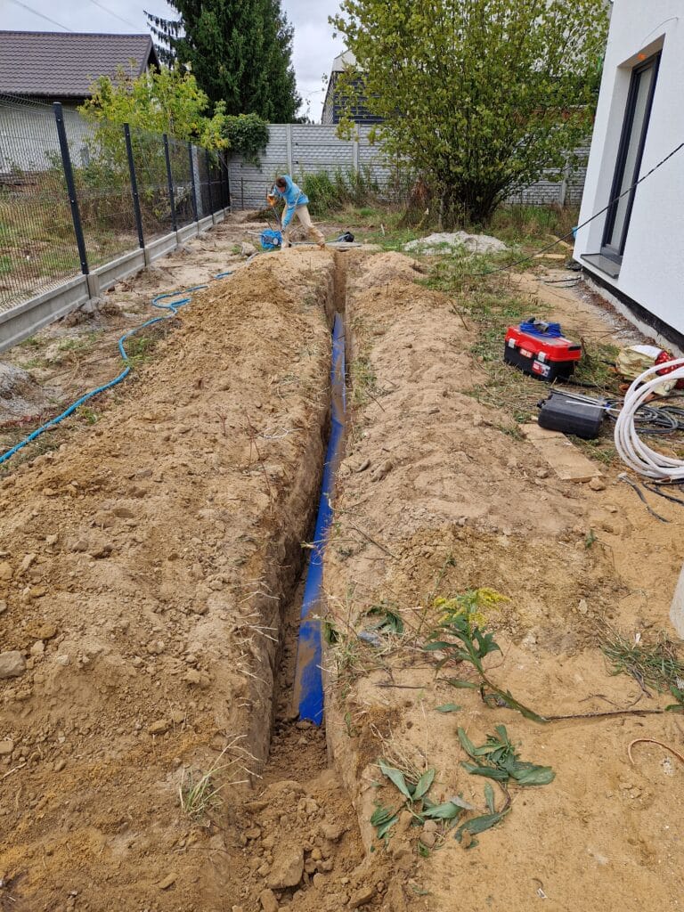 Profesjonalne układanie rury PE przyłącza wodnego Hydromonters.pl w głębokim wykopie (poniżej strefy przemarzania) obok nowego budynku.