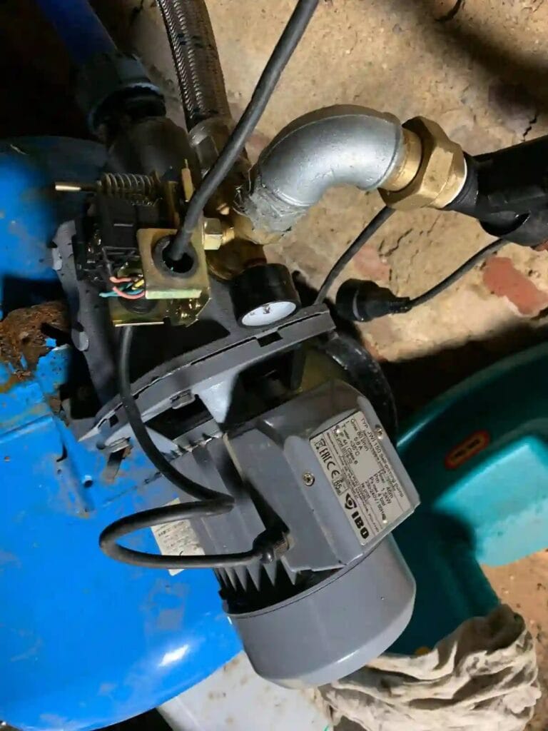 Zniszczony mechaniczny wyłącznik ciśnieniowy (presostat) na pompie hydroforowej IBO JSW-150 w wilgotnej piwnicy.