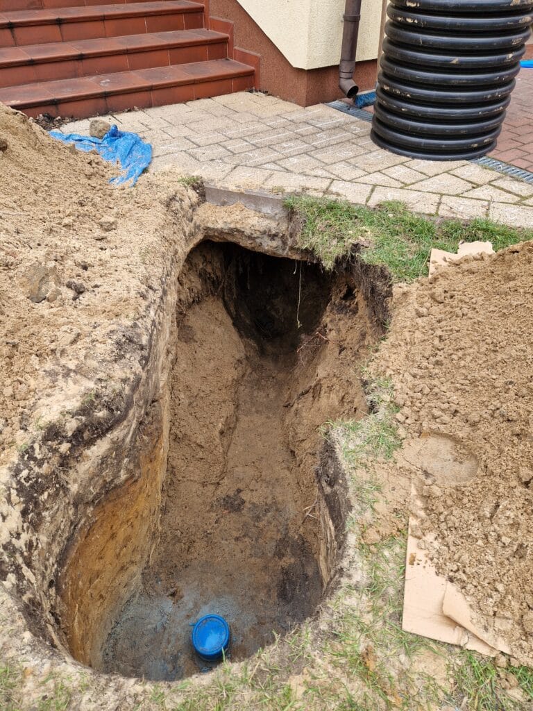 Wyczerpujący przecisk (podkop) horyzontalny Hydromonters.pl pod chodnikiem i schodami, aby ułożyć przyłącze studni głębinowej bez niszczenia nawierzchni.