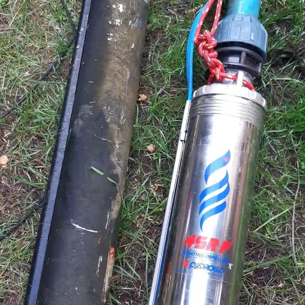 Profesjonalna wymiana pompy głębinowej: nowa pompa premium Pedrollo 4SRF obok starej, pokrytej osadem rury tłocznej PE.