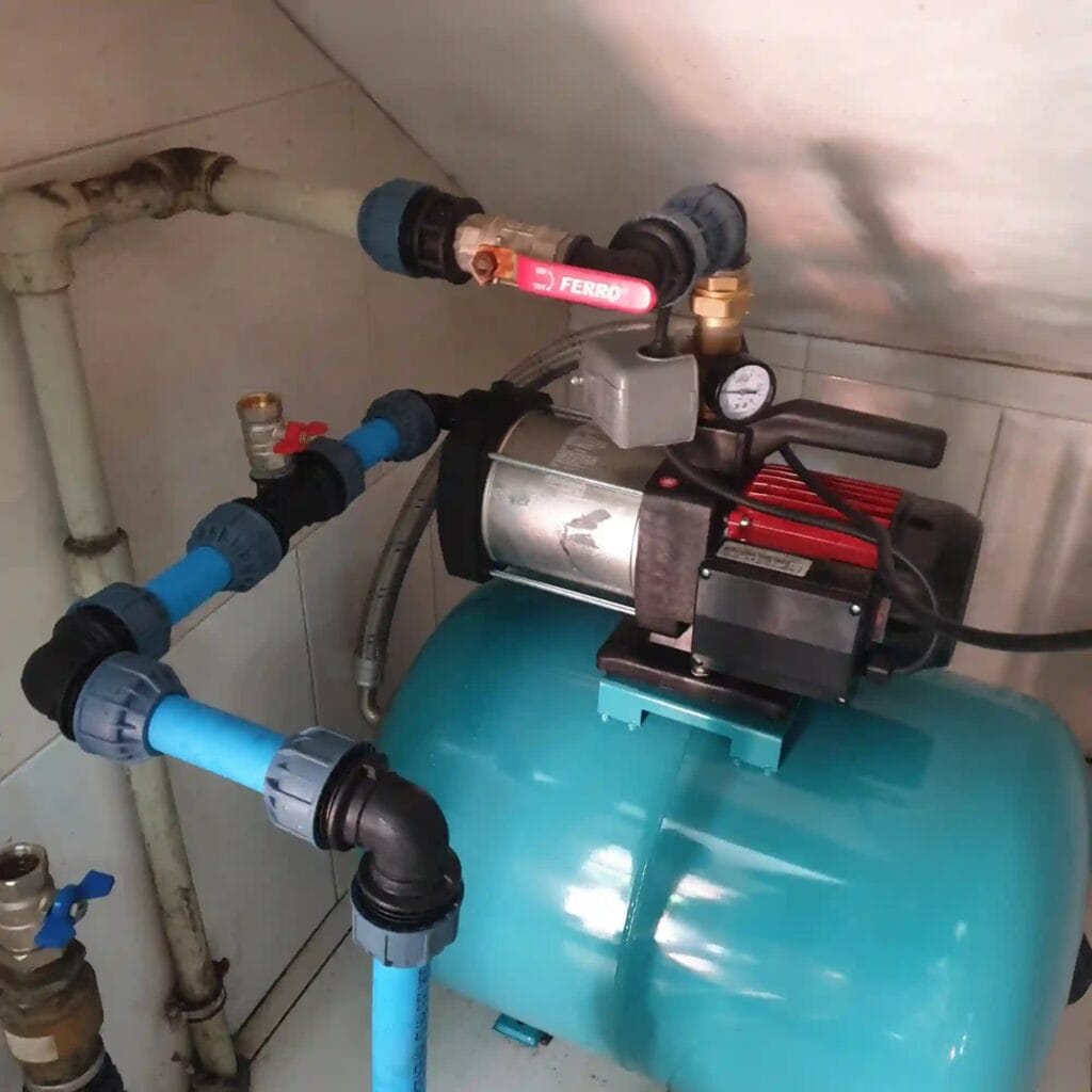 Czysty montaż pompy Leader Multi HWA (czerwony silnik). Widoczna integracja nowego systemu PE (niebieskie rury) ze starą instalacją PP (białe rury).