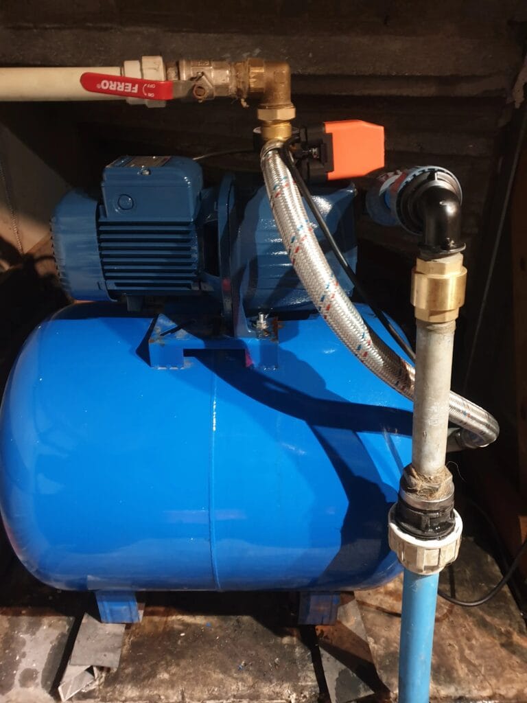 Stabilnie zainstalowany zestaw hydroforowy z pompą Pedrollo JSWm, niebieskim zbiornikiem przeponowym i wyłącznikiem ciśnieniowym PSG