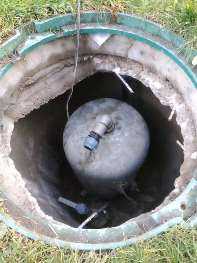 Krytyczny błąd: stary zbiornik ocynkowany wciśnięty do ciasnej studni kręgowej, co całkowicie uniemożliwia jego obowiązkowy serwis.